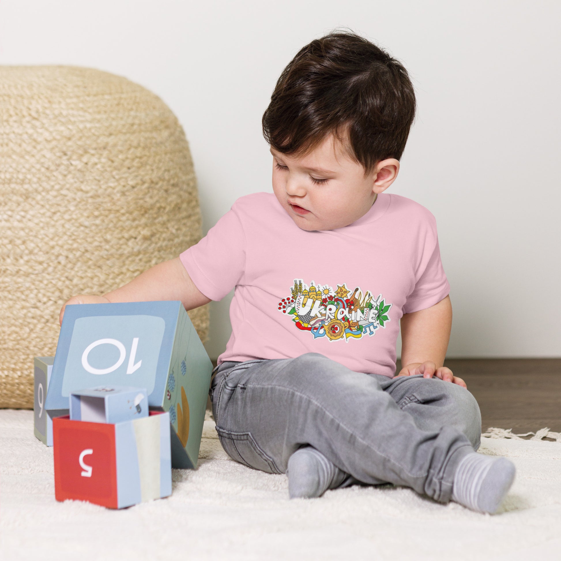 Toddler wearing Ukraine design t-shirt playing with blocks, showcasing style and comfort in 100% cotton tee.