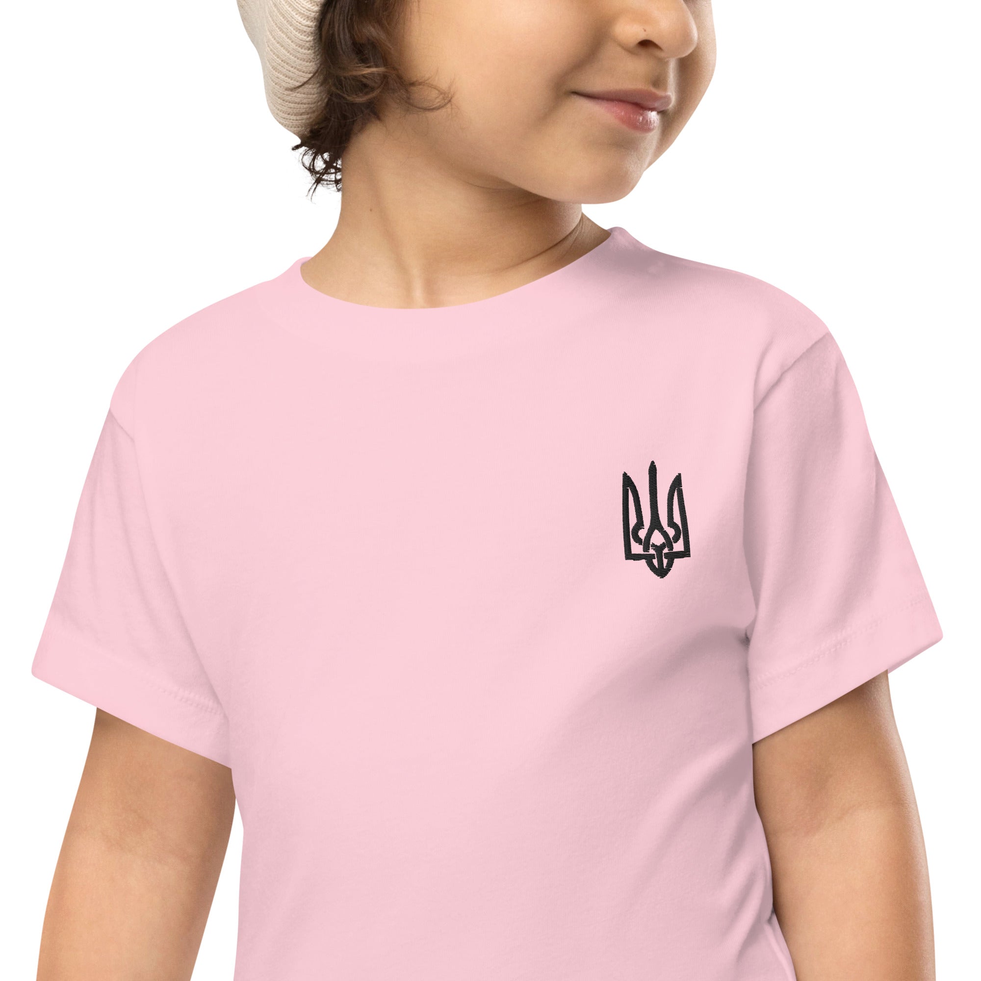 Toddler wearing a pink short-sleeve tee with Ukrainian Tryzub print, made from soft 100% cotton for comfort and durability.
