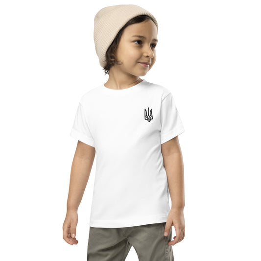 Toddler wearing a white short sleeve tee with Ukrainian Tryzub print, paired with khaki pants and a beige beanie.