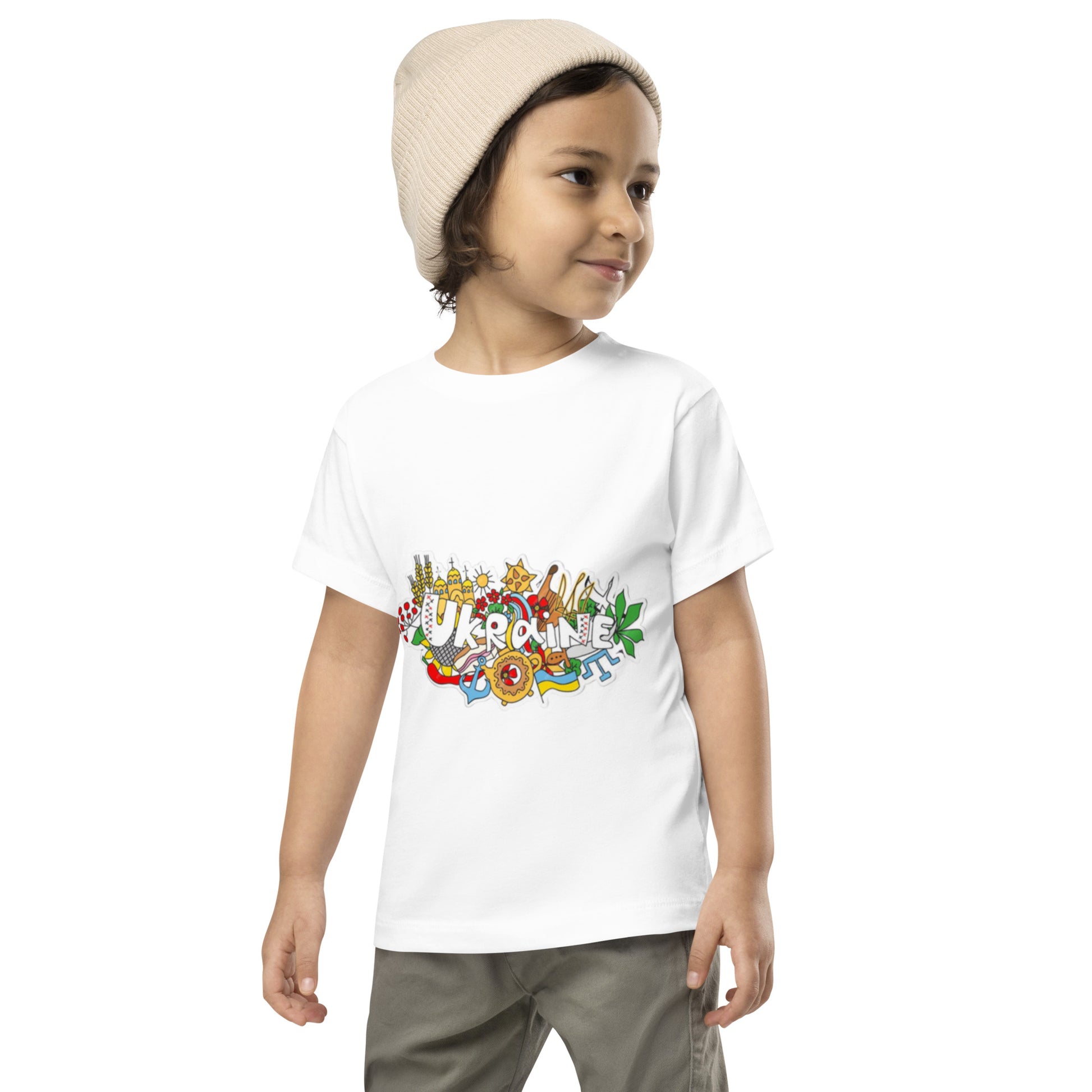 Toddler wearing Ukraine design short sleeve t-shirt, beige beanie, and khaki pants, showcasing cultural pride and casual style.