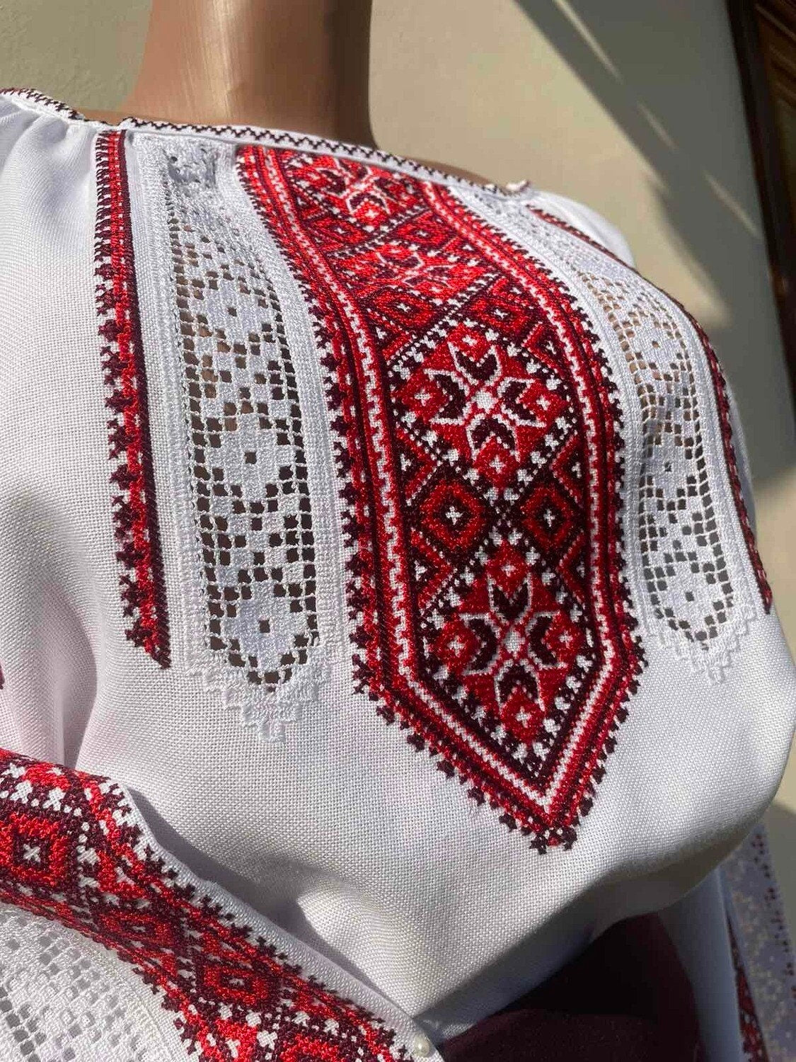 Traditional Ukrainian Vyshyvanka blouse with intricate red embroidery in cross-stitch on white cotton fabric.