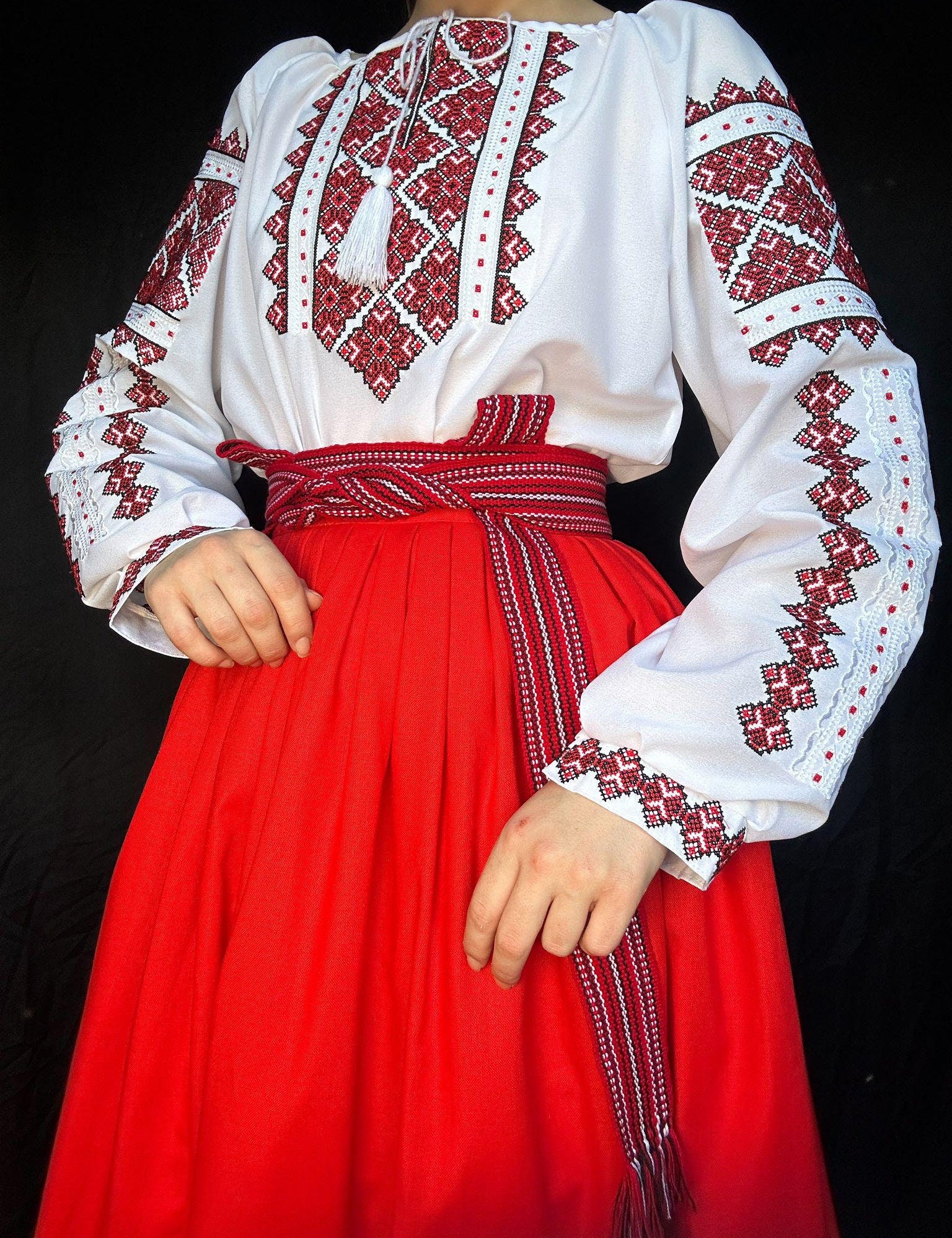Traditional Ukrainian Vyshyvanka blouse with red cross-stitch embroidery on white fabric, paired with a red skirt.