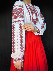 Traditional Ukrainian Vyshyvanka blouse with red embroidery, ethnic cross-stitch design on white chiffon fabric.