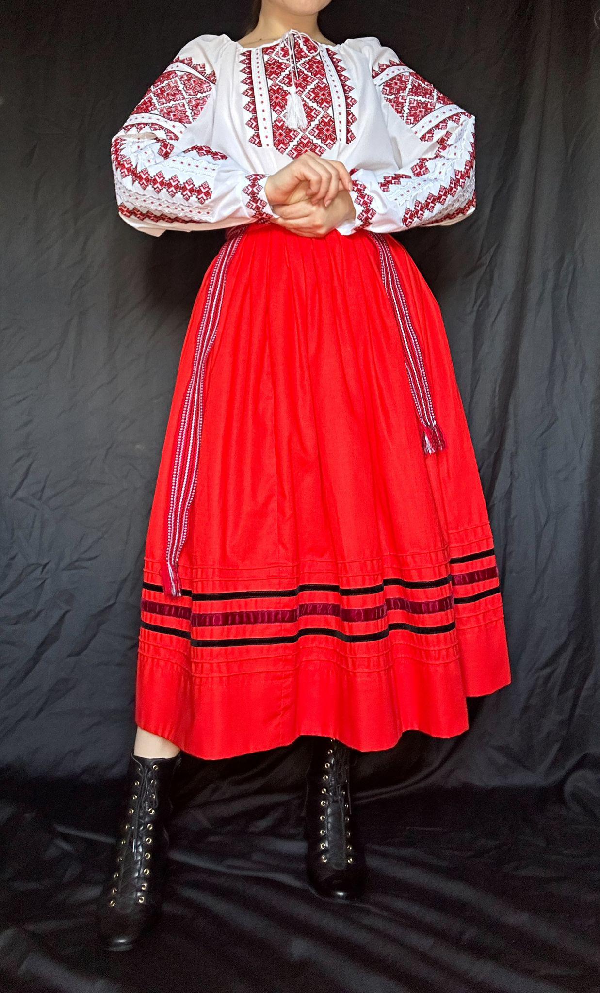 Woman wearing traditional Ukrainian embroidered Vyshyvanka blouse with red skirt, showcasing ethnic cross-stitch craftsmanship.