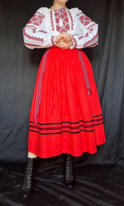 Woman wearing traditional Ukrainian embroidered Vyshyvanka blouse with red skirt, showcasing ethnic cross-stitch craftsmanship.