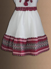 Traditional Ukrainian girl's costume with embroidered blouse and skirt, featuring intricate red and black folk patterns.