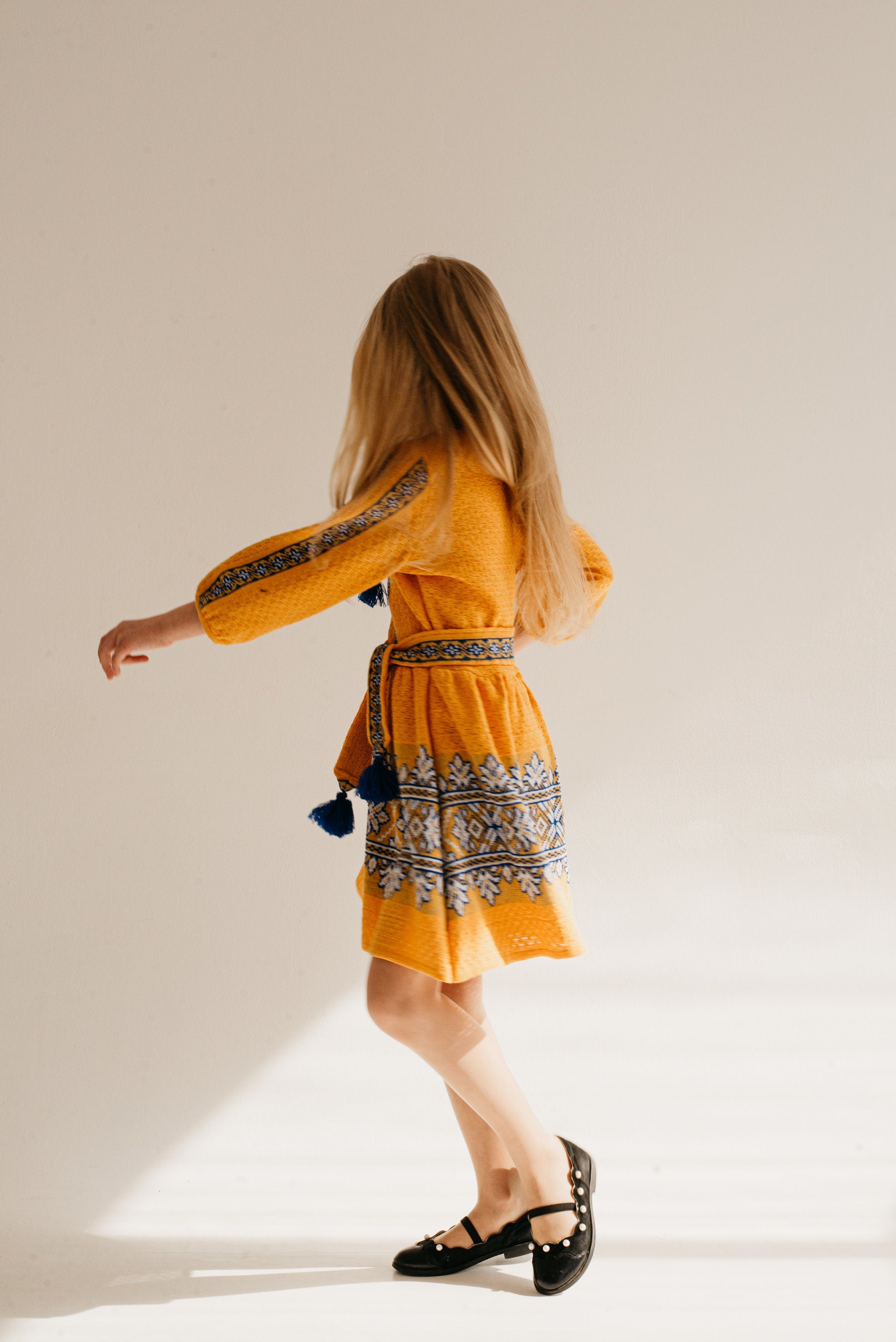 Girl wearing a traditional Ukrainian golden dress with blue and white embroidery, showcasing cultural elegance and modern comfort.