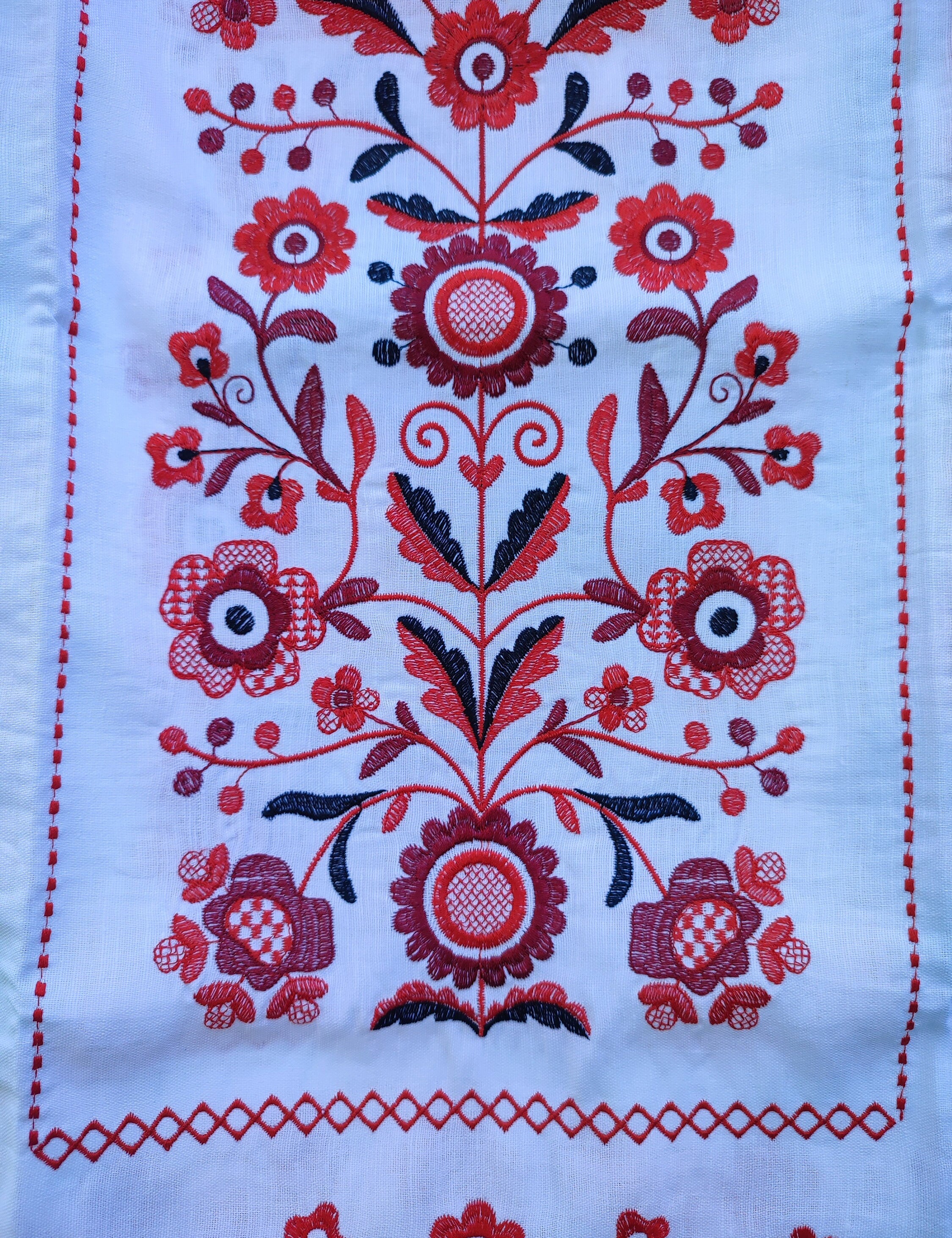 Traditional Ukrainian wedding rushnyk with red floral embroidery design on white linen fabric.