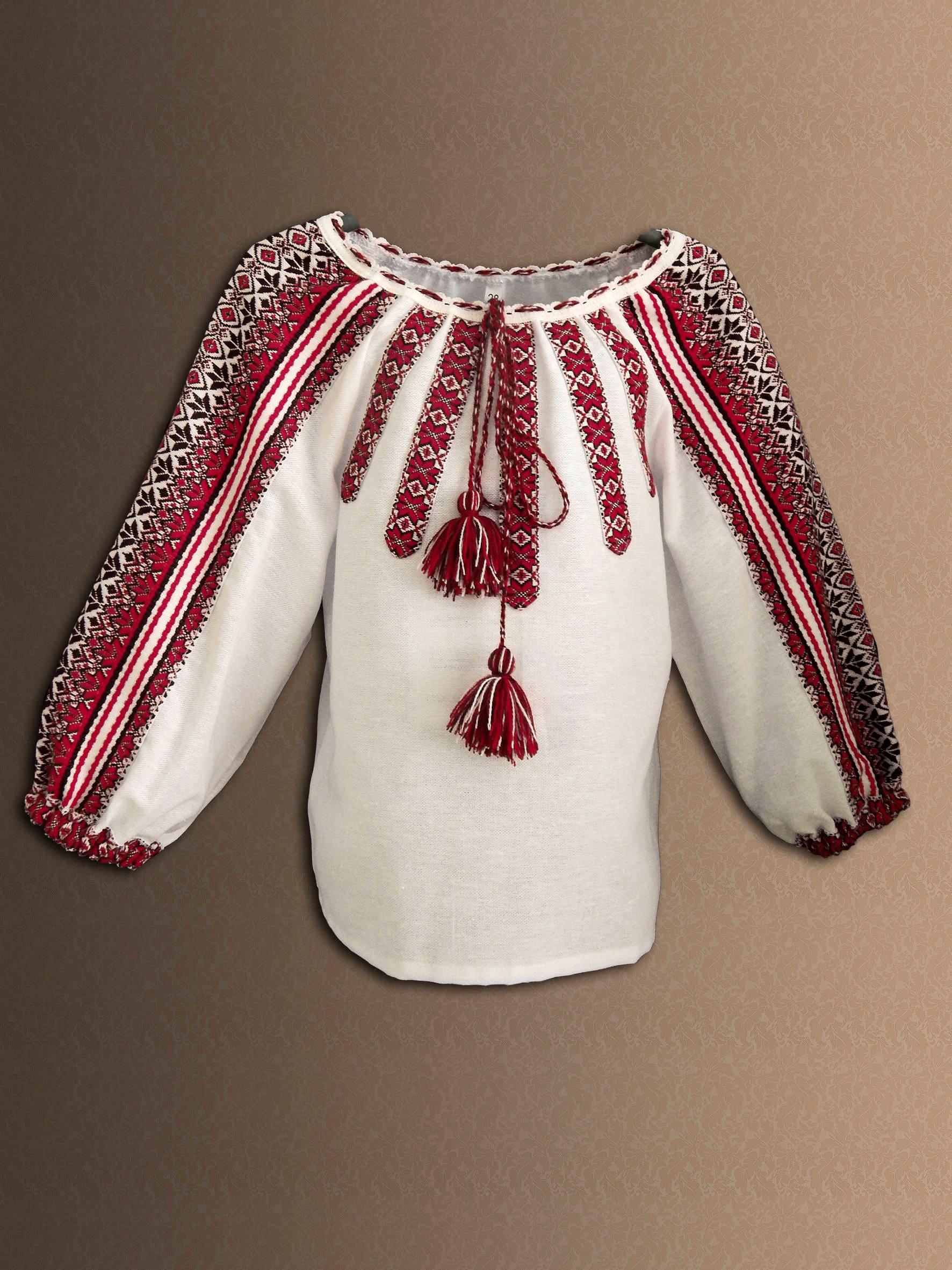 Traditional Ukrainian embroidered girl's blouse with red and white folk design, part of a Vyshyvanka costume set for girls.