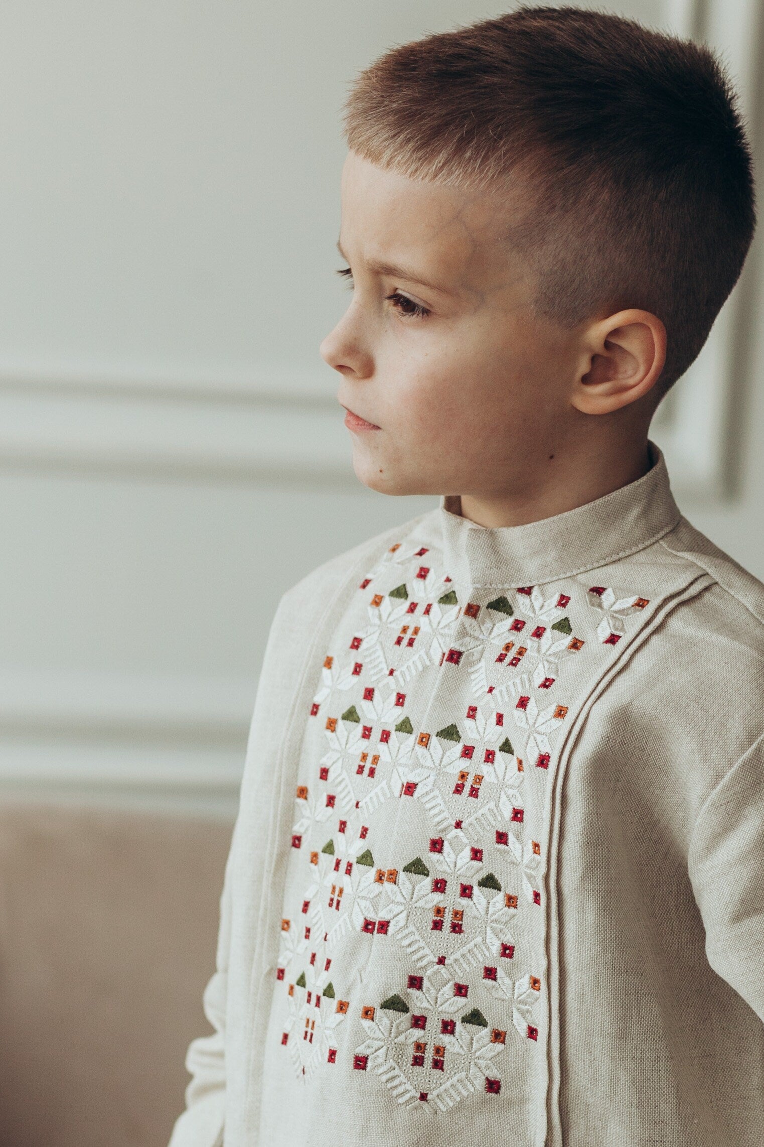 Boy wearing Ukrainian embroidered vyshyvanka shirt with long sleeves, featuring traditional patterns on white linen.