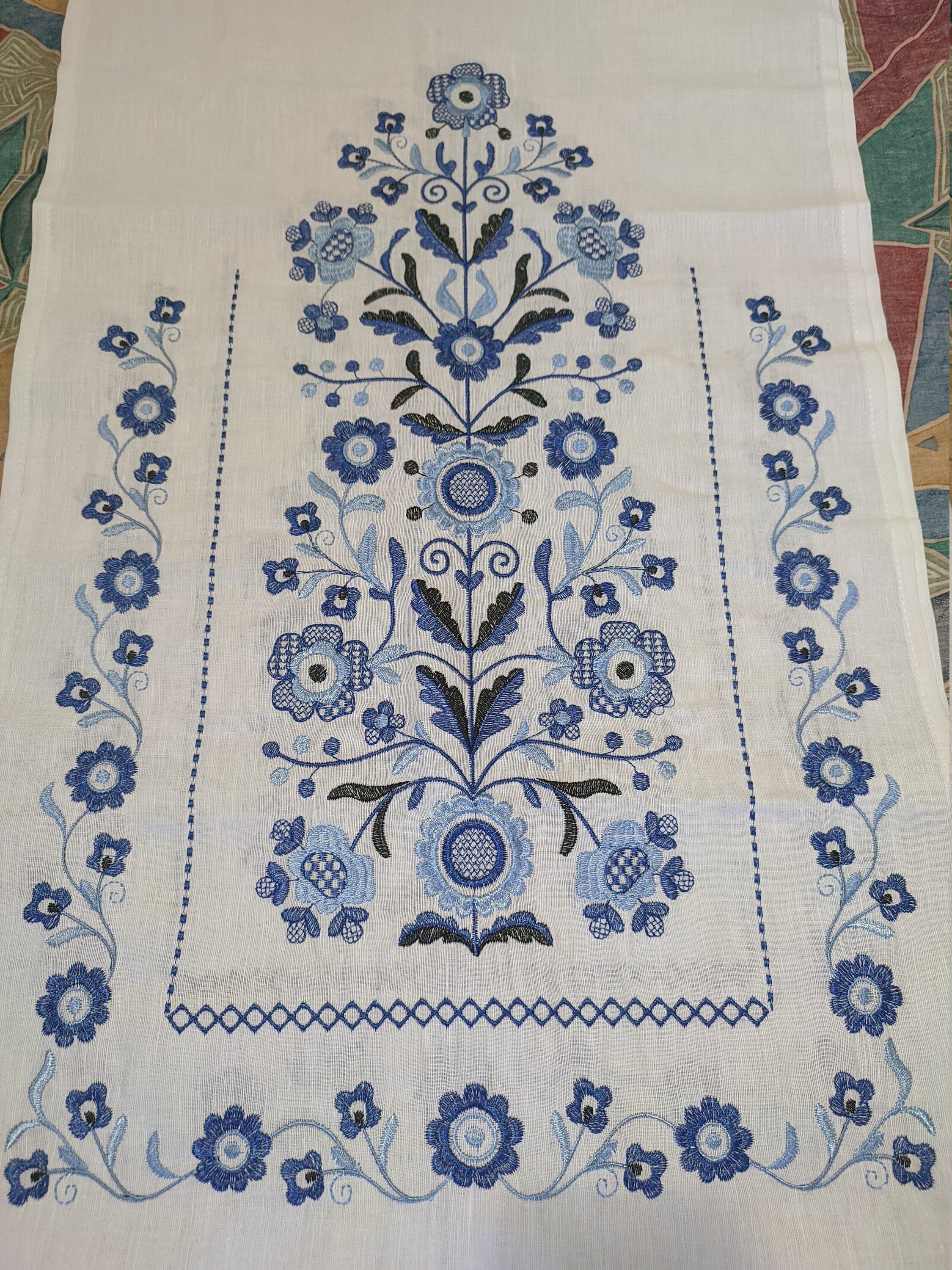 Traditional Ukrainian rushnyk with Tree of Life embroidery in blue on white linen, symbolizing prosperity and protection.