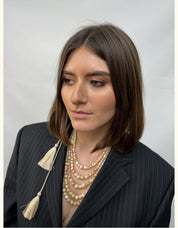 Woman wearing 2025 Ukrainian Balamut necklace crafted from golden mother-of-pearl, styled with a pinstripe jacket.