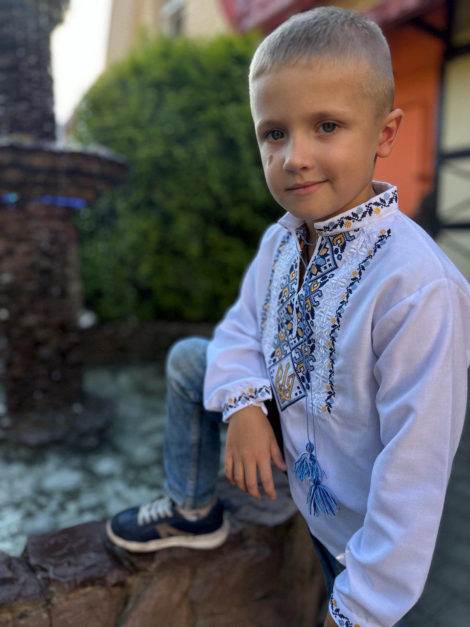 Young boy wearing Ukrainian embroidered vyshyvanka shirt with blue and yellow Tryzub design, symbolizing heritage and identity.