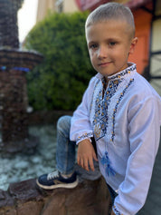Young boy wearing Ukrainian embroidered vyshyvanka shirt with blue and yellow Tryzub design, symbolizing heritage and identity.