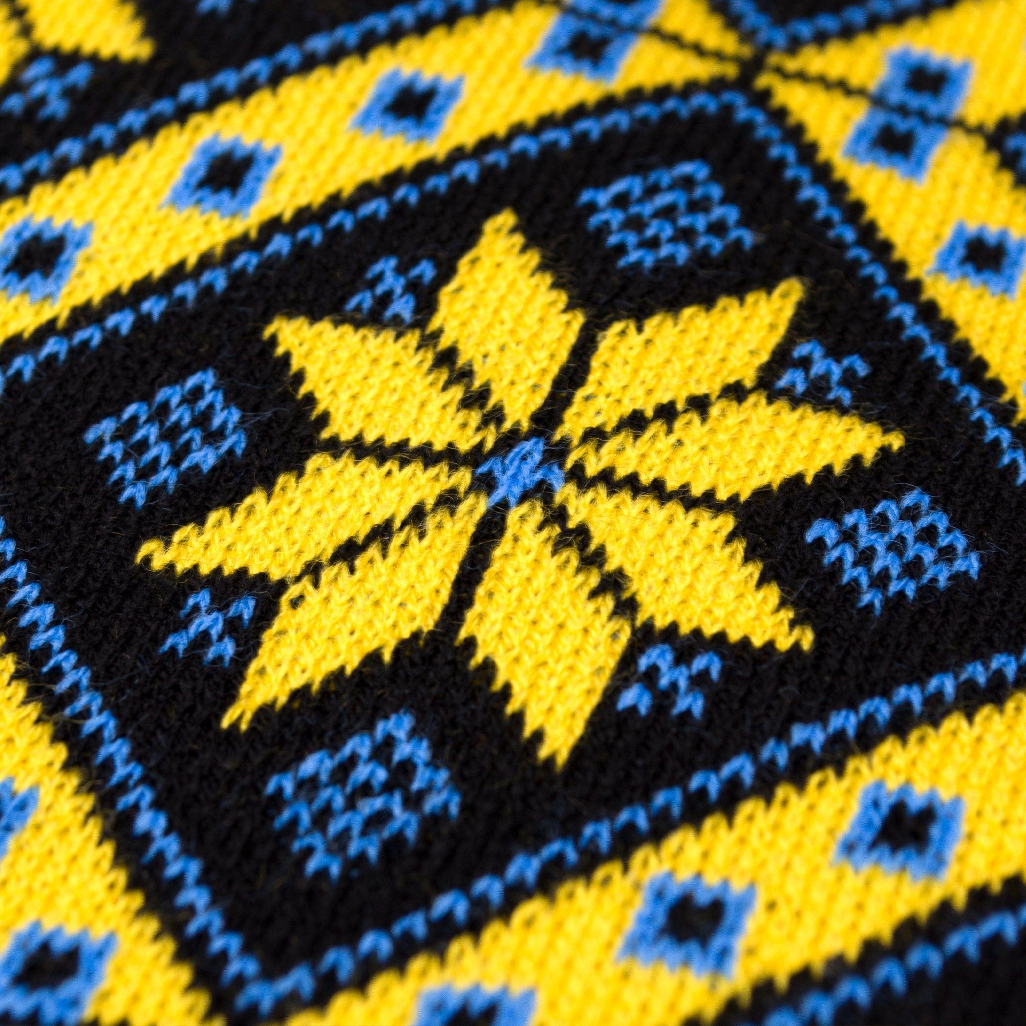 Close-up of knit scarf with traditional yellow and blue geometric pattern inspired by Ukrainian artistry for winter warmth.