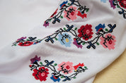 Close-up of Ukrainian embroidered floral blouse with colorful cross-stitch design, traditional Vyshyvanka style for girls.