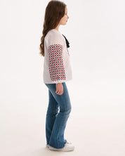 Side view of girl in Ukrainian embroidered blouse with traditional patterns and blue jeans.