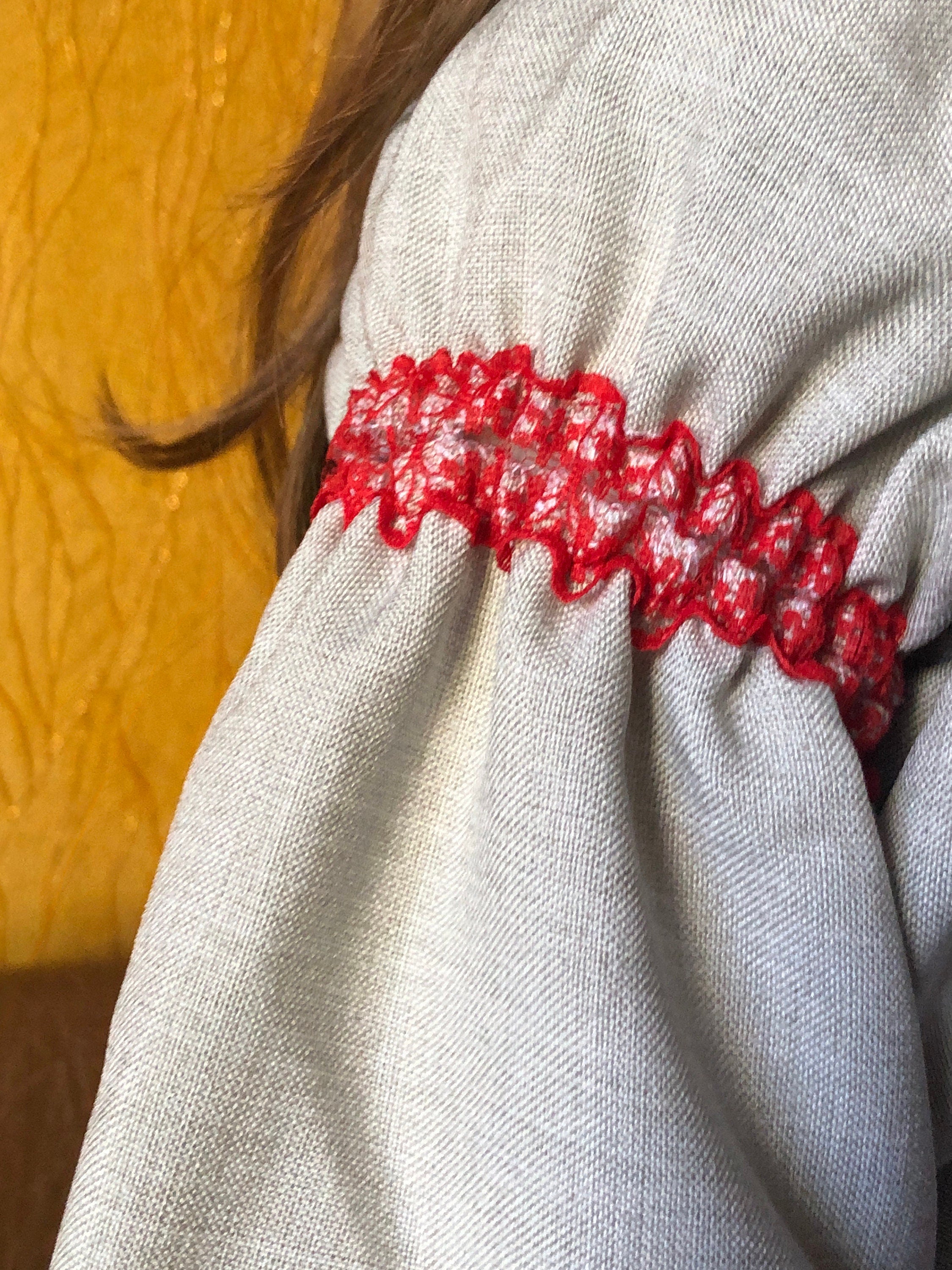 Close-up of Ukrainian embroidered linen dress sleeve with red floral Rosava motif, highlighting traditional Vyshyvanka style for girls.