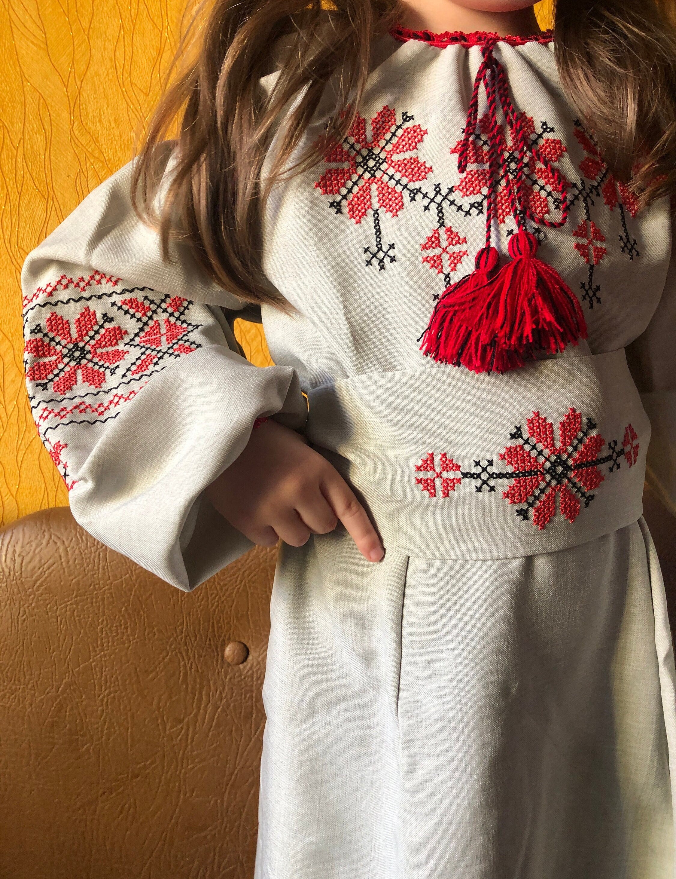 Girl wearing traditional Ukrainian embroidered linen dress with red floral patterns and a belt