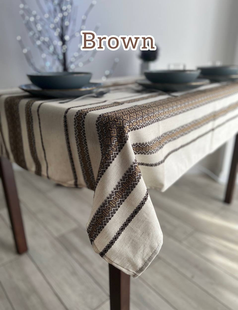 Brown Ukrainian embroidered linen tablecloth with ethnic patterns on a dining table, made from 100% natural fabric.