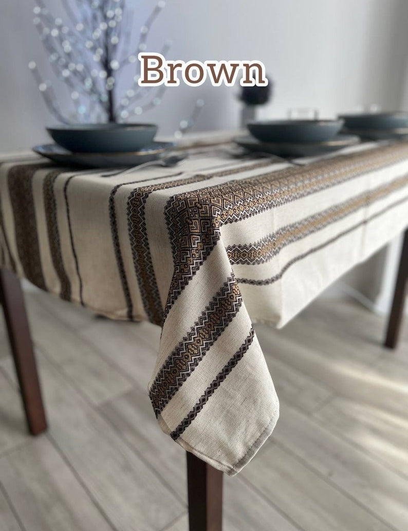 Brown Ukrainian embroidered linen tablecloth with ethnic patterns on a dining table, crafted from 100% natural fabric.