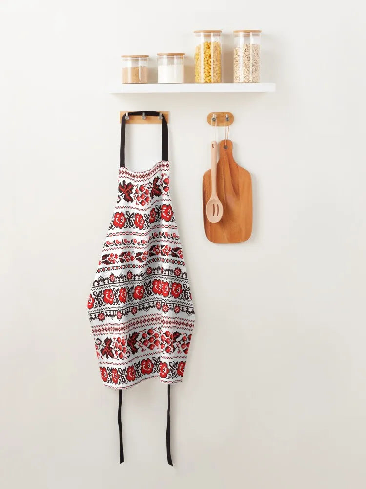 Ukrainian embroidered pattern apron hanging on wall in kitchen setting with wooden utensils and jars.