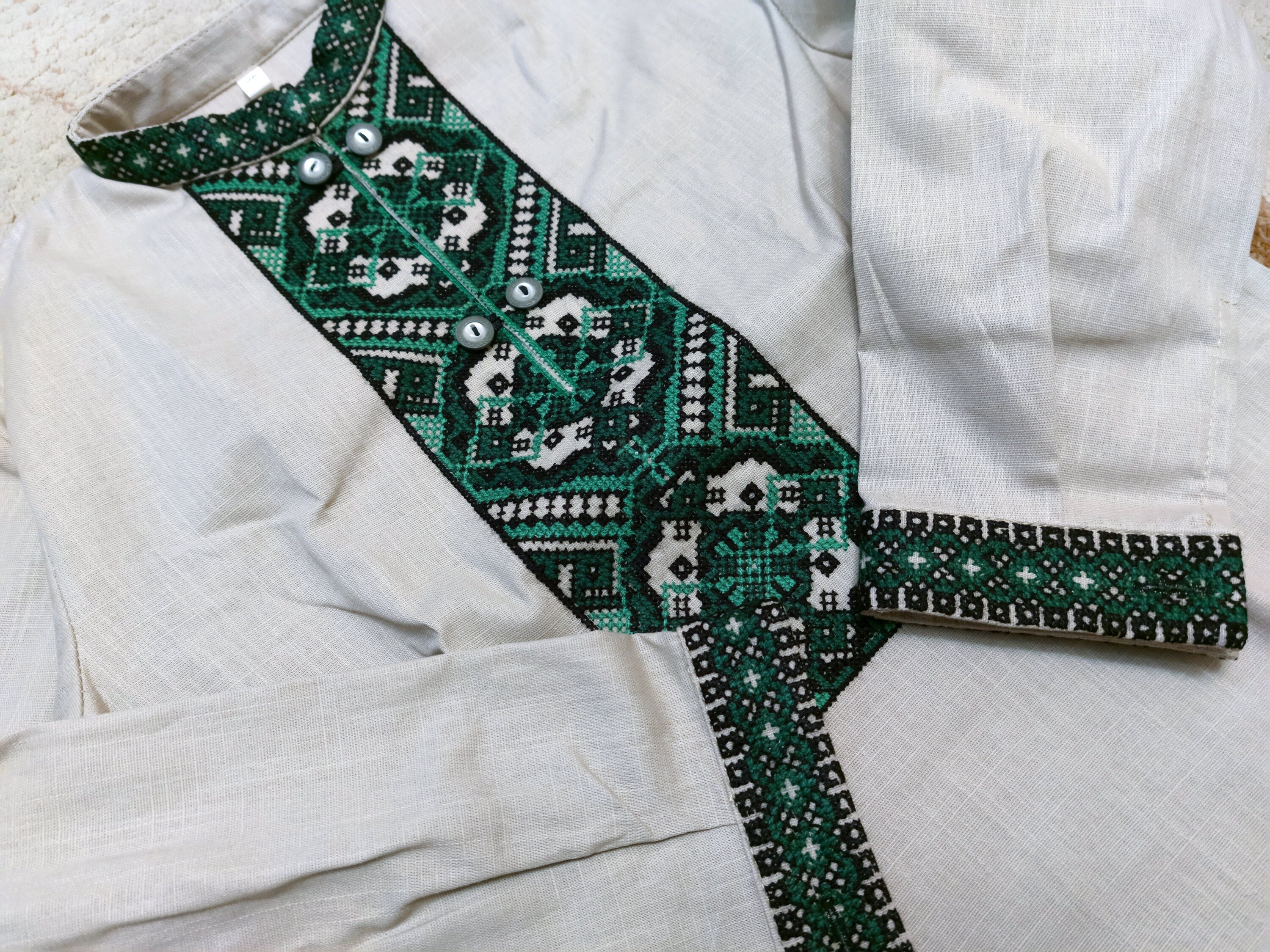 Ukrainian embroidered shirt for boys, featuring green cross-stitch patterns on natural beige linen, traditional vyshyvanka design.