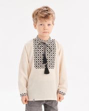 Boy wearing Ukrainian embroidered vyshyvanka shirt in Slavic folk style with intricate black and white designs.