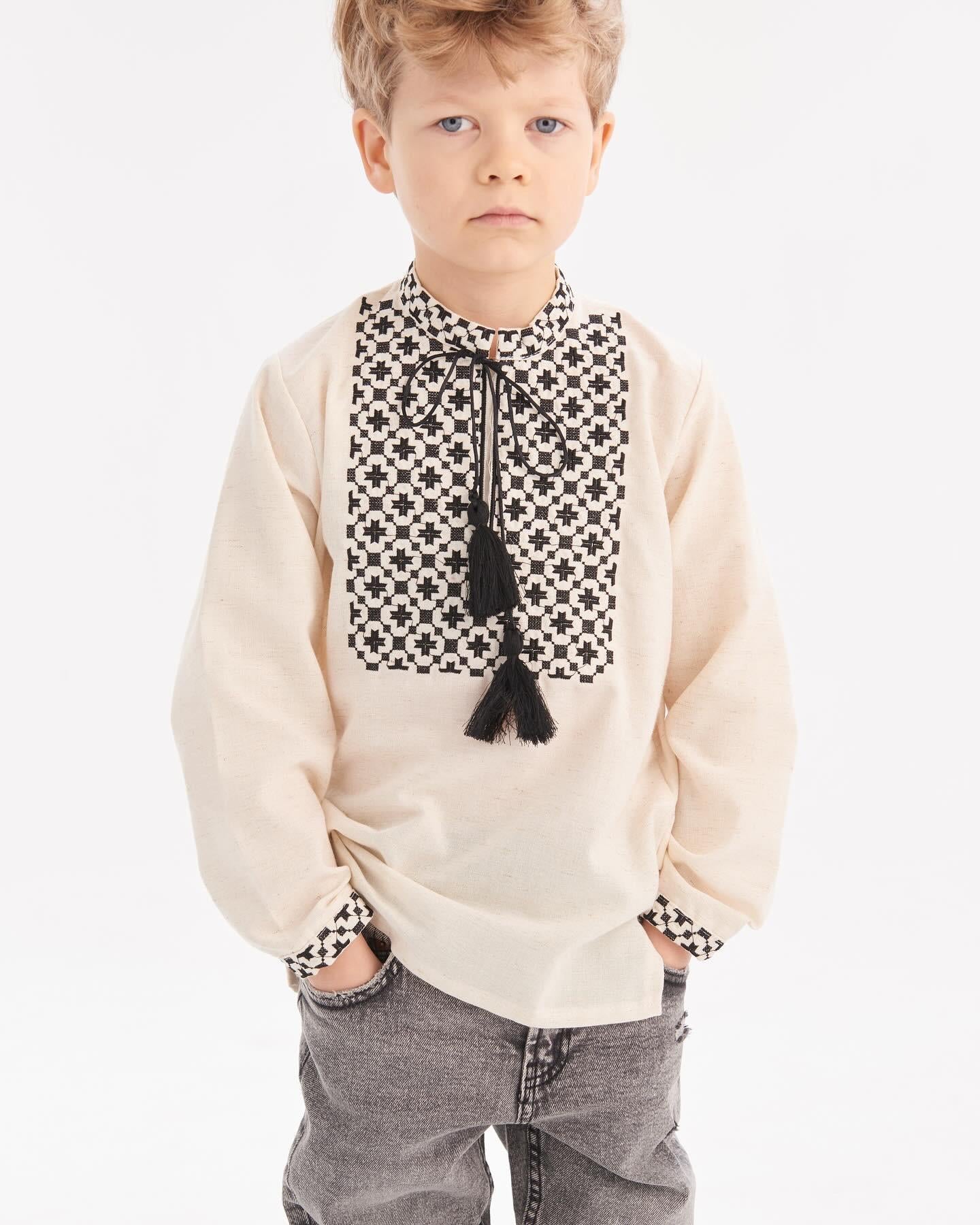 Boy wearing Ukrainian embroidered shirt with Slavic folk design, showcasing intricate patterns on beige fabric.