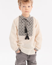 Boy wearing Ukrainian embroidered shirt with Slavic folk design, showcasing intricate patterns on beige fabric.