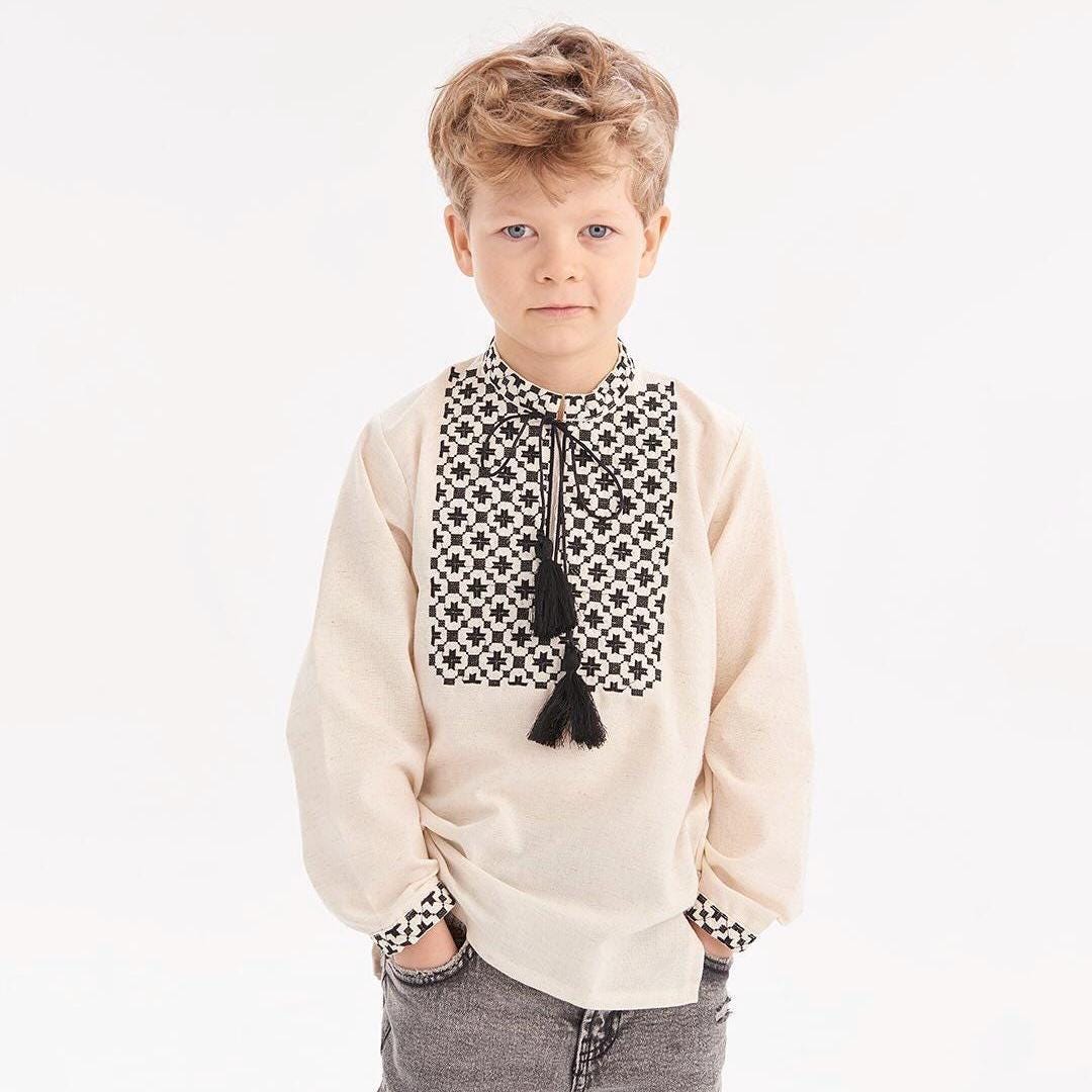 Boy wearing Ukrainian embroidered shirt with Slavic folk style design, featuring black and white intricate patterns.