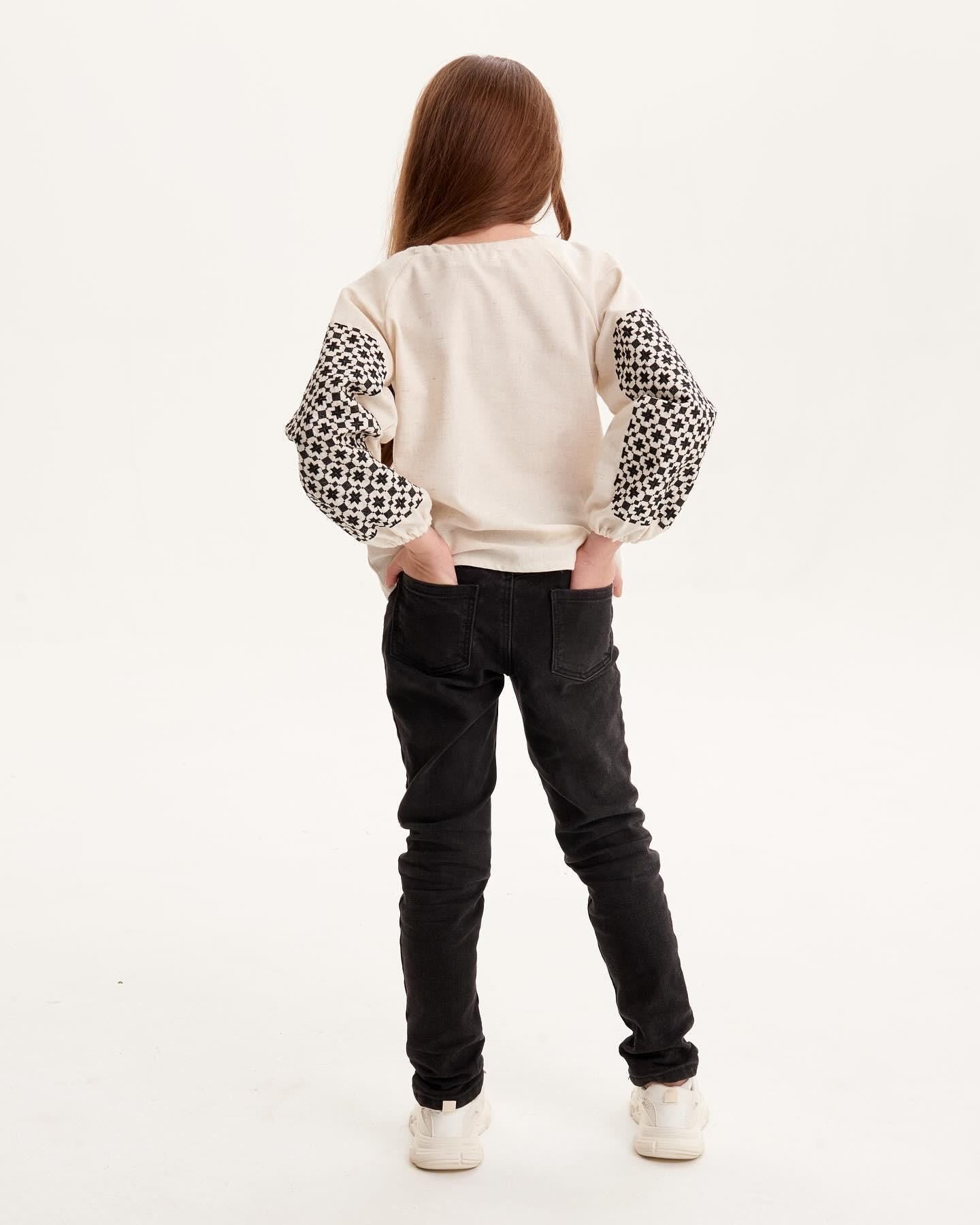 Girl wearing Ukrainian embroidered shirt with Slavic folk motifs, back view.