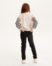 Girl wearing Ukrainian embroidered shirt with Slavic folk motifs, back view.