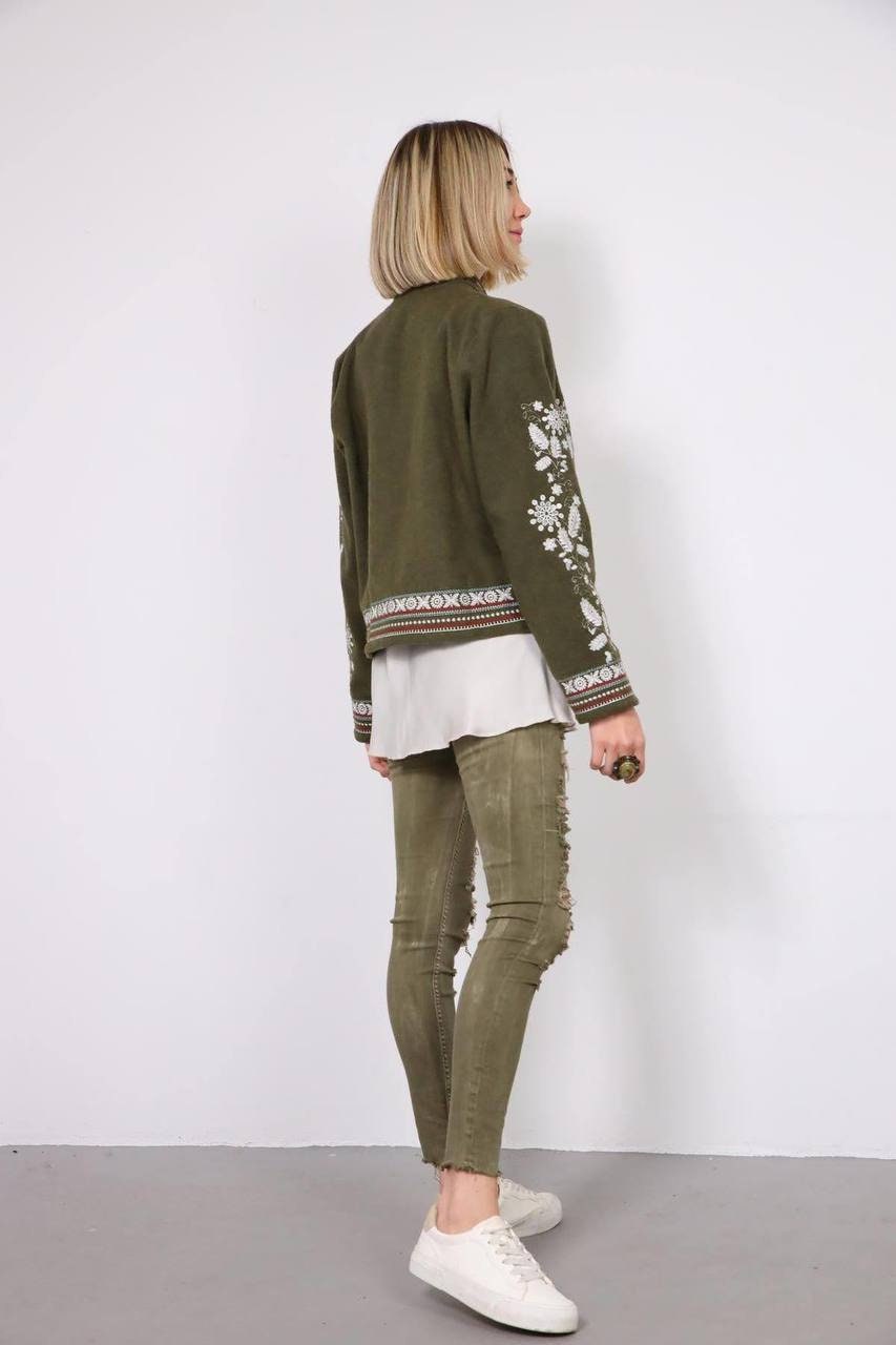 Woman wearing khaki embroidered Vyshyvanka jacket with Ukrainian patterns, casual and elegant style, side view.