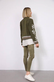 Woman wearing khaki embroidered Vyshyvanka jacket with Ukrainian patterns, casual and elegant style, side view.