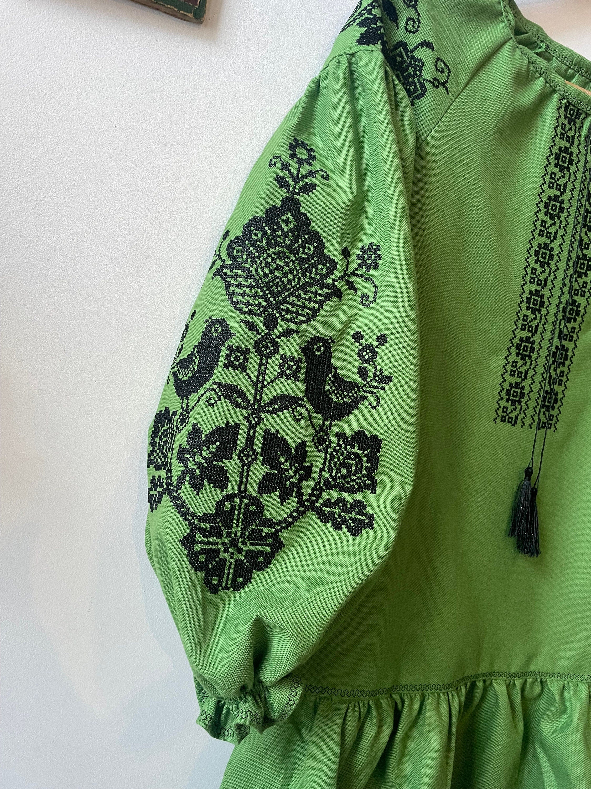 Green Vyshyvanka dress with black floral embroidery on sleeve, showcasing traditional Ukrainian style.