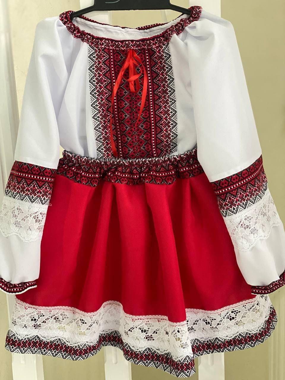 Traditional Ukrainian embroidered girl's blouse and skirt in red and white with intricate patterns, showcasing ethnic fashion.