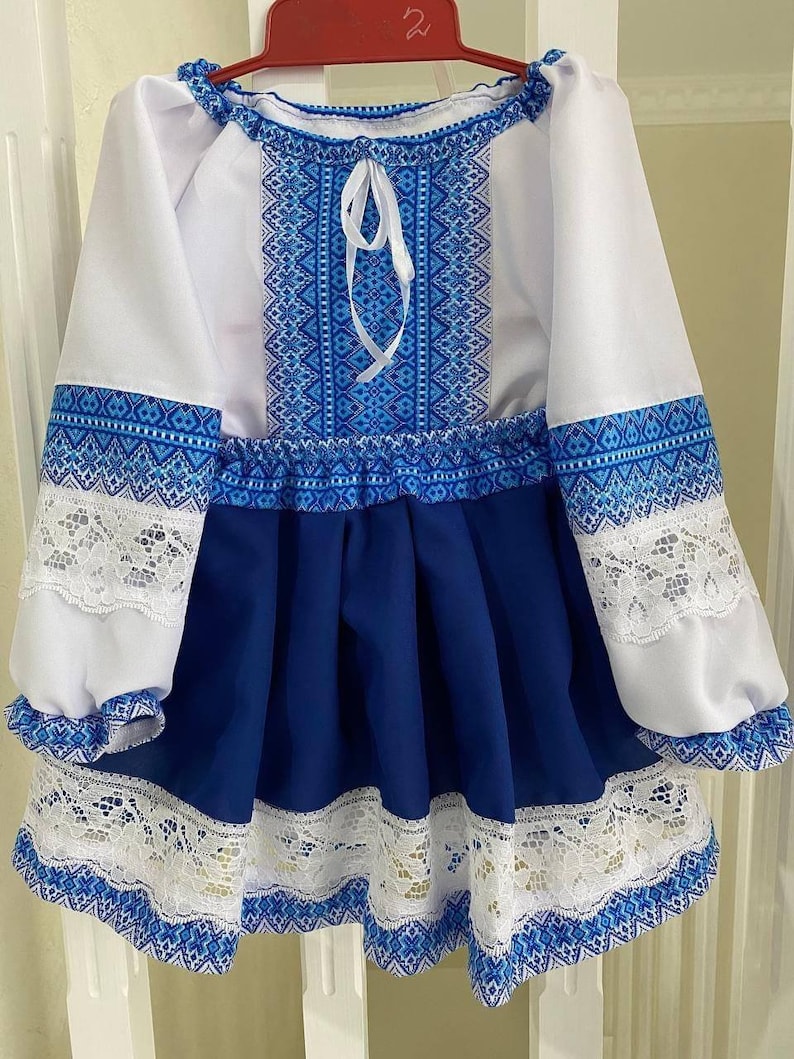 Traditional Ukrainian girl's embroidered blouse and skirt in blue and yellow with lace details, perfect for cultural occasions.