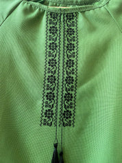 Close-up of black embroidered design on green Ukrainian Vyshyvanka dress.