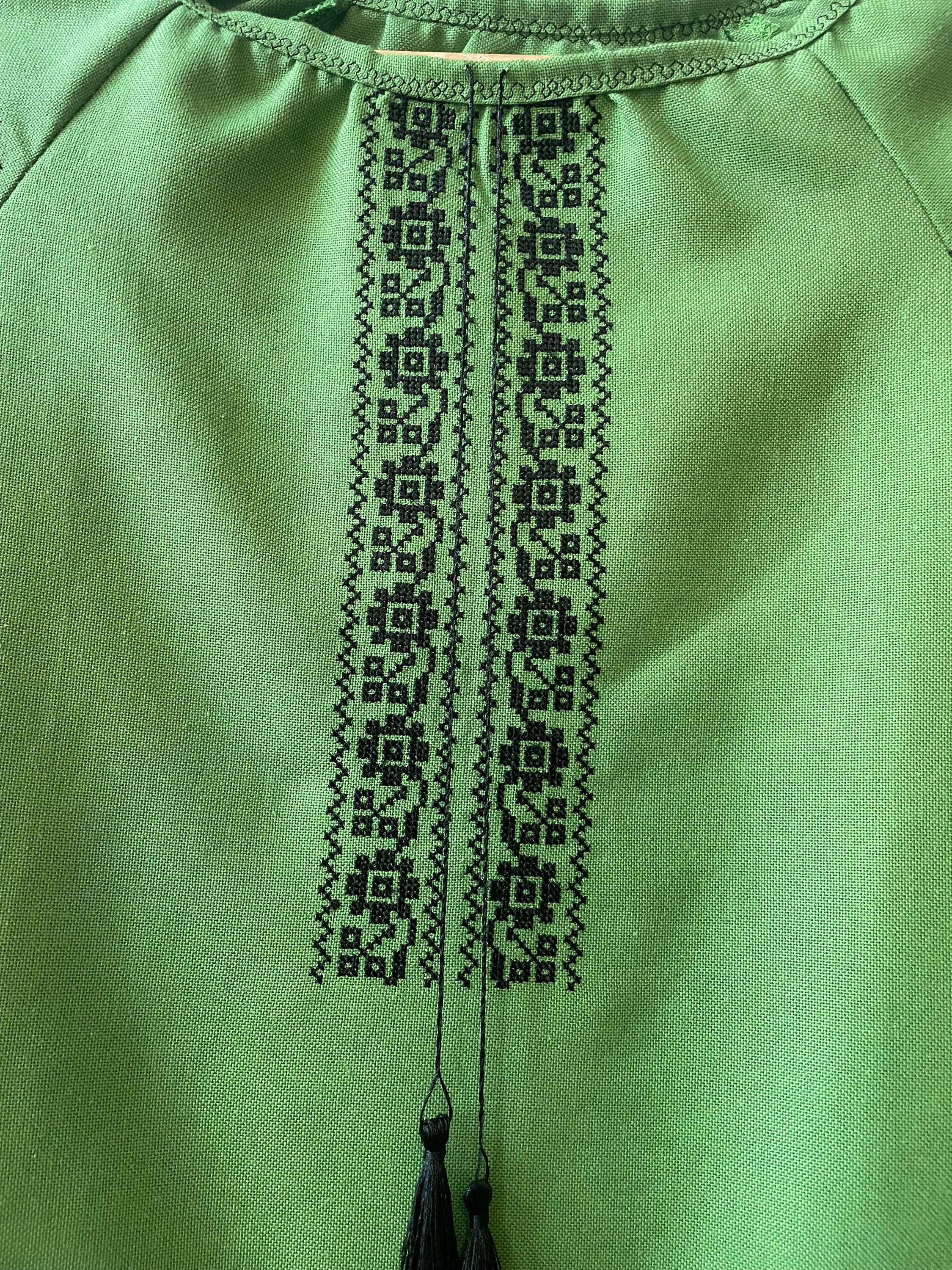 Close-up of black embroidered design on green Ukrainian Vyshyvanka dress.