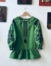 Green Ukrainian embroidered dress with black floral patterns, Vyshyvanka Boho style, featuring long sleeves and a tassel accent.