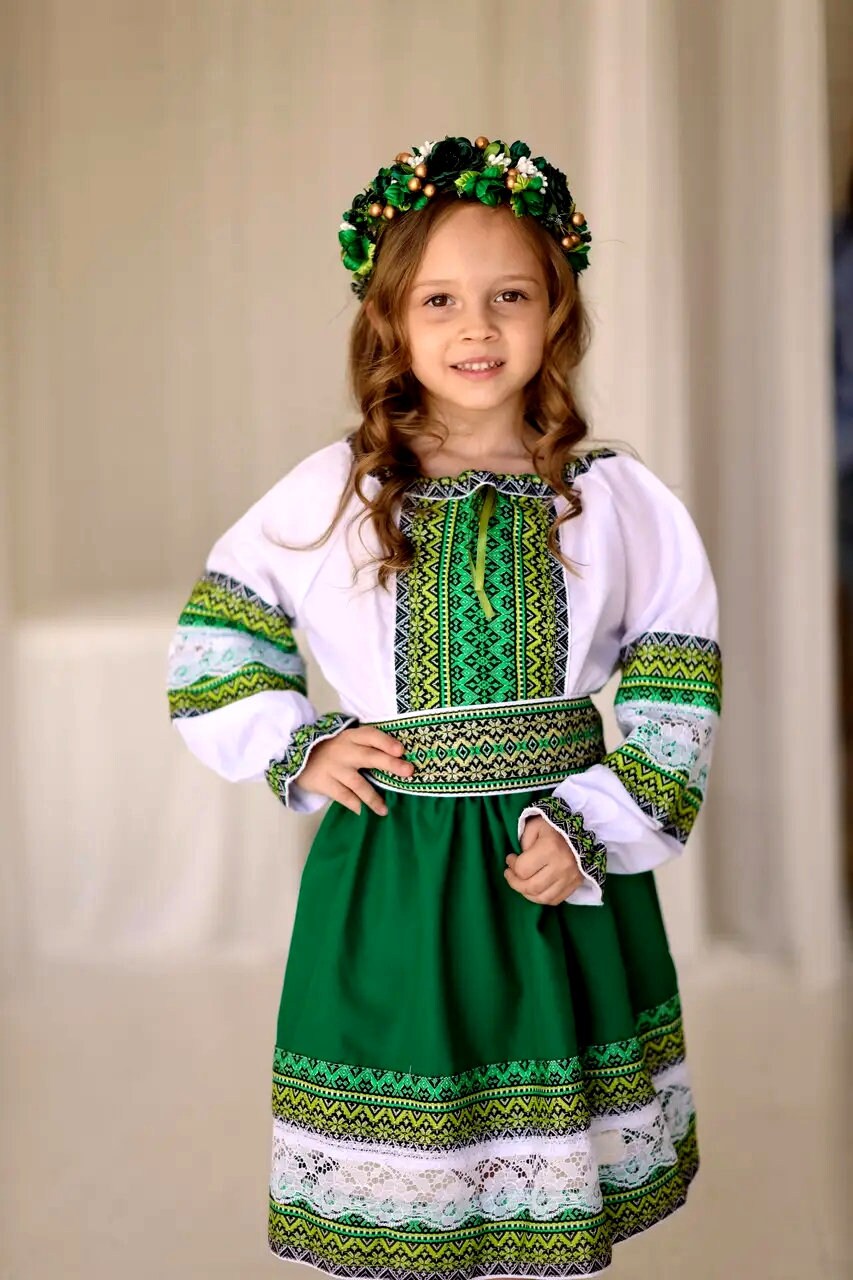 Girl wearing a traditional Ukrainian embroidered blouse and skirt set with green and white design, ideal for cultural celebrations.