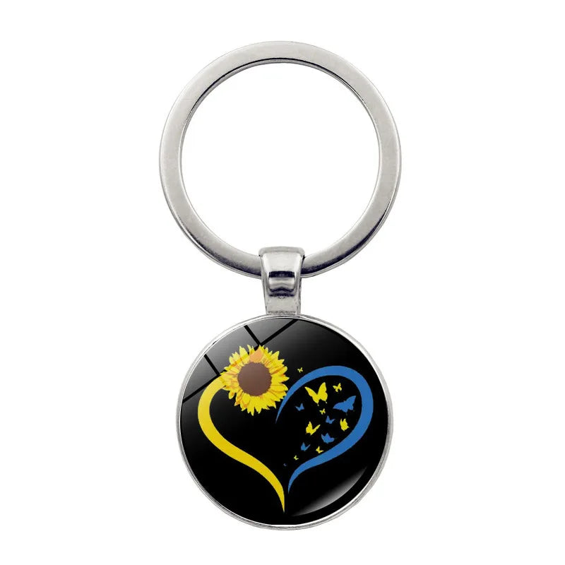 Ukrainian glass keychain with sunflower and heart emblem, symbolizing cultural pride and style.