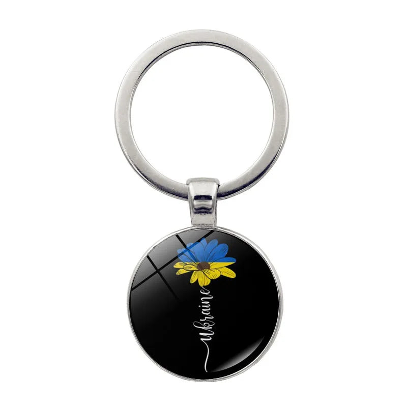 Ukrainian glass keychain with blue and yellow emblem, showcasing cultural pride and style.