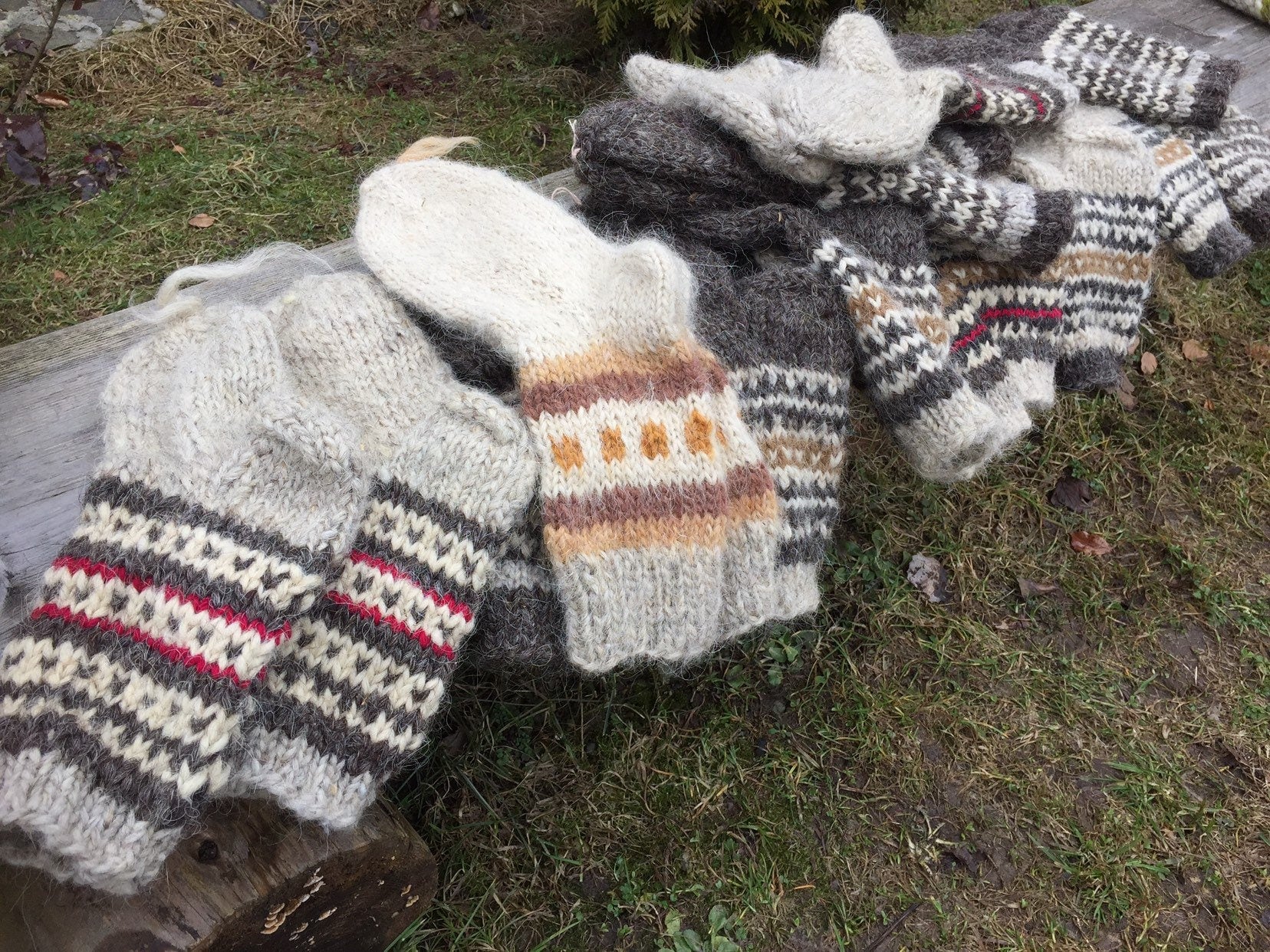 Hand-knitted wool socks from Ukraine with colorful patterns laid on a wooden bench outdoors.