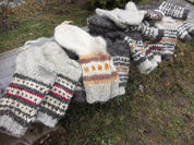 Hand-knitted wool socks from Ukraine with colorful patterns laid on a wooden bench outdoors.