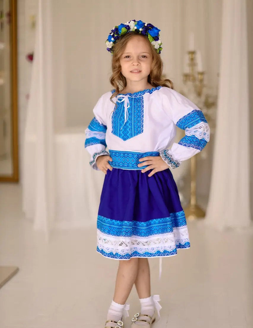 Girl wearing Ukrainian Hutsul folk costume, blue blouse and skirt with lace, traditional attire for cultural events and celebrations.