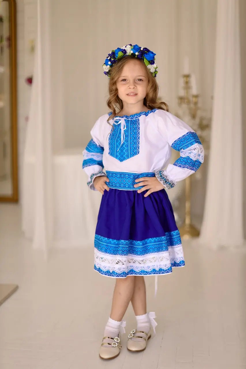 Girl wearing Ukrainian Hutsul folk costume, blue blouse and skirt with lace, traditional attire for cultural events and celebrations.