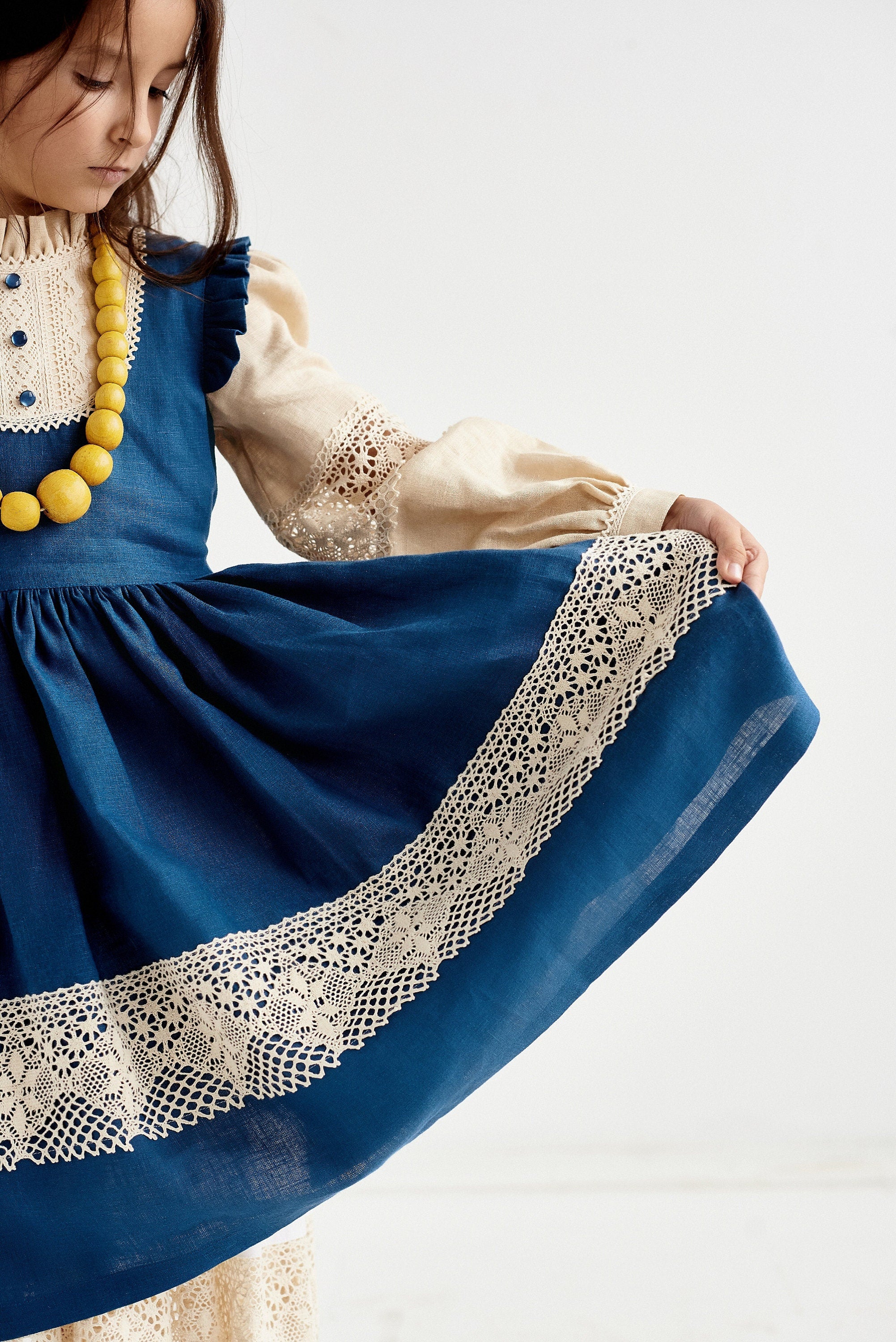 Blue Ukrainian linen dress for baby girl with lace trim and puff sleeves, featuring a traditional boho style.