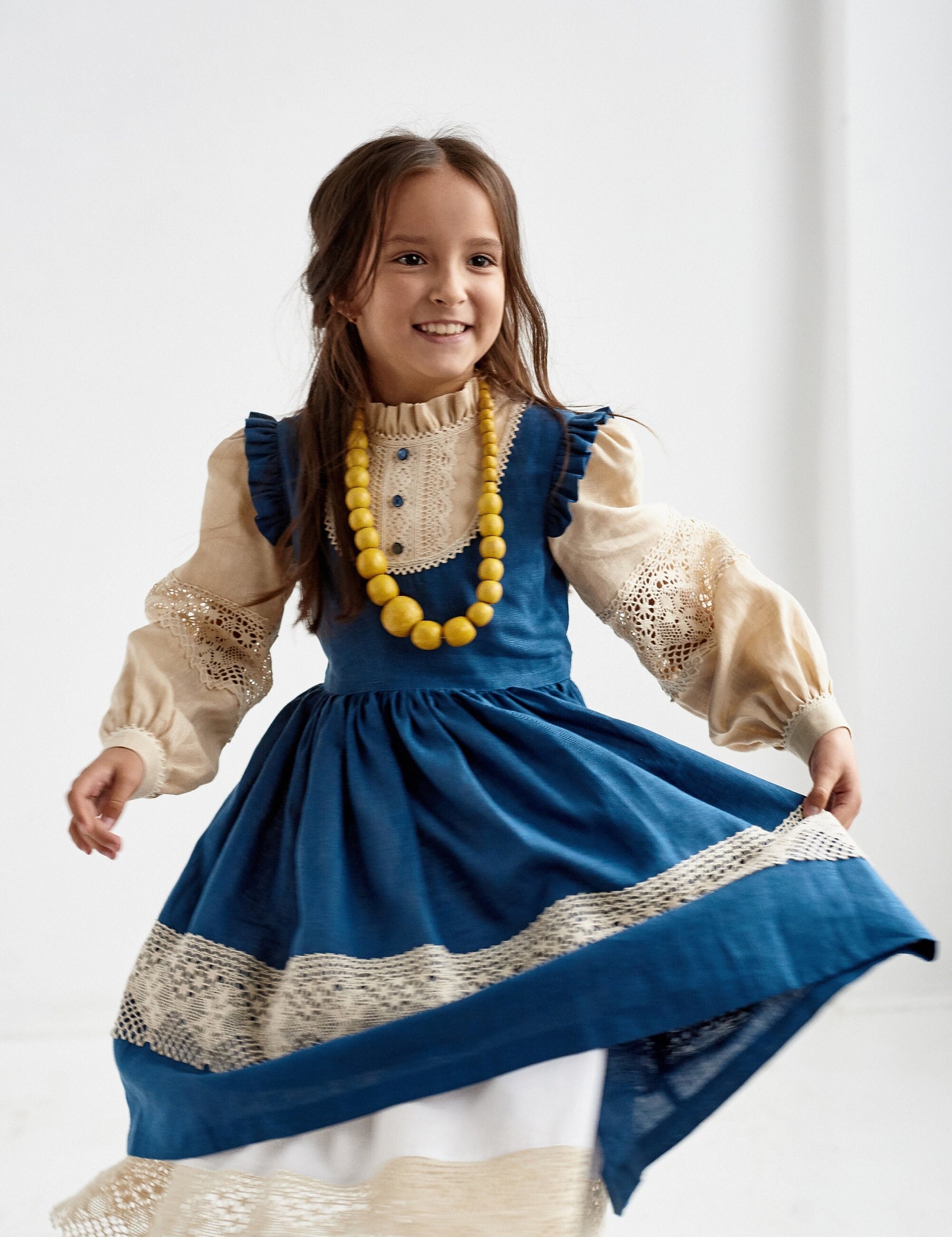Alt Tag: Girl wearing a blue Ukrainian linen Vyshyvanka dress with lace trim and long puff sleeves, perfect for special occasions.